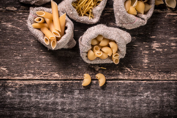 Fototapeta na wymiar Various mix of pasta on wooden rustic background. Diet and food