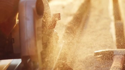 Man is craft working at a work bench with power tools in slowmotion during sunset with beautiful lens flare. 1920x1080 - Powered by Adobe