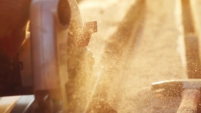 Man is craft working at a work bench with power tools in slowmotion during sunset with beautiful lens flare. 1920x1080