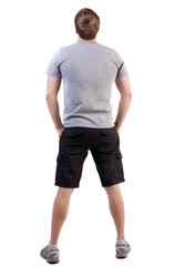 Fototapeta premium Back view of handsome man in t-shirt and shorts looking up. Standing young tourist. Rear view people collection. backside view of person. Isolated over white background.