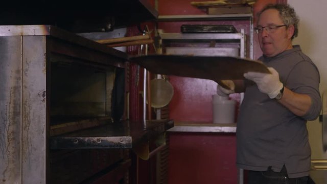 Chef takes pizza out of the oven - 4K