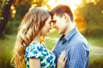 Lovers having touched their heads are in the last rays of the sun on the field.