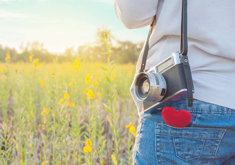 Young woman photographer with retro camera and red Heart in flow