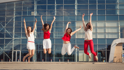 Young girls raise their hands while jumping outside
