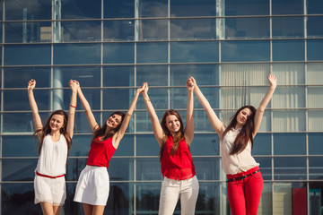 Fototapeta premium Young ladies dressed in red and white raise their hands holding