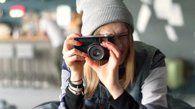 Hipster girl sitting in the restaurant and doing photo by old camera
