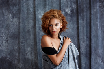 Young beautiful african girl posing, wrapping up  in grey cloth.