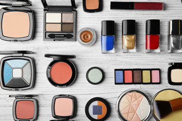 Cosmetic products and brushes on wooden background