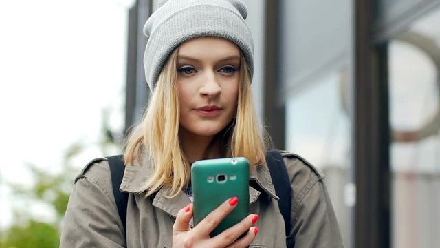 Hipster girl smoking cigarette and browsing internet on smartphone
