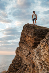 Young sportsman standing on the mountain rock by the sea