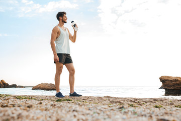 Young sporty man athlete resting after jogging and drinking water