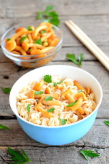 Pasta recipe with marinated mushrooms and fresh parsley. Pasta in a dish, marinated mushrooms in glass bowl, chopsticks on wooden background. Closeup