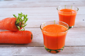 Glasses of carrot juice on a wooden table.