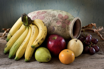 still life photography : many fruit with old vase on old wood and grunge background