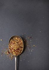 Aerial view of an antique silver spoon full of peri peri spices, on a rustic slate background forming a page border