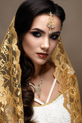 Beautiful girl in Indian style with a scarf on her head. Model with a creative and bright makeup....