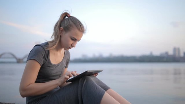 Portrait of a beautiful girl with a tablet in his hands at sunset
