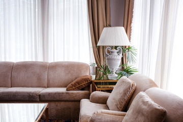 Living room interior in warm tones. Two leather sofas with cushions, lamp on the table