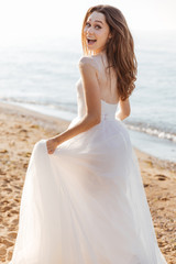 Fototapeta na wymiar Young beautiful woman in wedding dress on beach