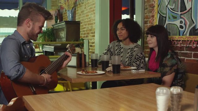 Three friends eating pizza and playing guitar - 4K