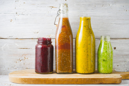 Bottles and jar with different smoothie on the white wooden background horizontal