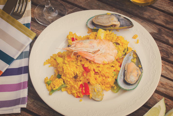 Paella served in plate on wooden table