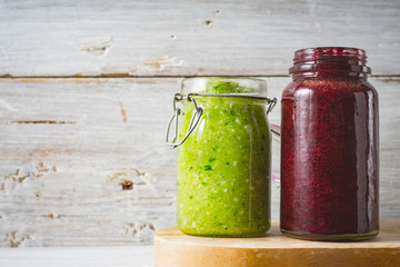 Green and red smoothie in the glass jar on the white wooden background