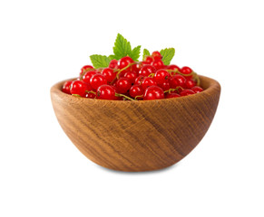 Redcurrant in a wooden bowl. Ripe and tasty currant isolated on white background. Red berries with leaves.