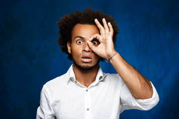 Young handsome african man posing over blue background.