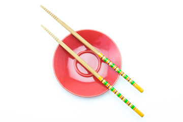 Plate with chopsticks on white background