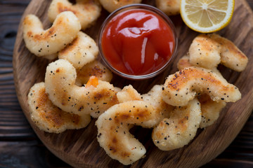 Wooden serving board with roasted panko breaded shrimps, closeup