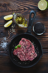 Frying pan with raw fresh tuna fillet and condiments, above view