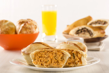 Empada Brazilian snack. pie with chicken on white plate on woode