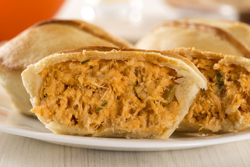 Empada Brazilian snack. pie with chicken on white plate on woode