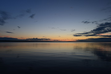 Fototapeta na wymiar Weather afterglow of summer sunset on lake water surface