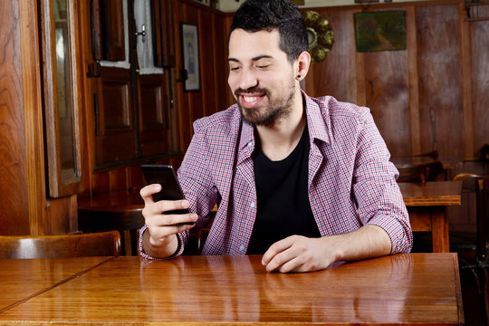 Latin man using his smartphone at a cafe.