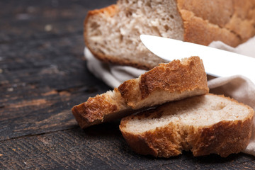 Fototapeta na wymiar Rustic bread on wood table. Dark woody background with free text space.