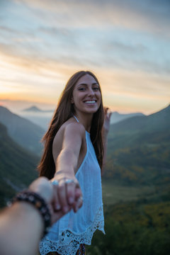 Beautiful brunette woman smiling at camera in mountains.Follow me.