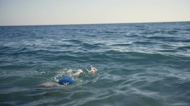 Child teen boy swims in the sea water.