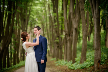 Bride and Groom at wedding Day walking Outdoors on spring nature. Bridal couple, Happy Newlywed woman and man embracing in green park. Loving wedding couple outdoor.