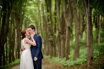 Bride and Groom at wedding Day walking Outdoors on spring nature. Bridal couple, Happy Newlywed woman and man embracing in green park. Loving wedding couple outdoor.