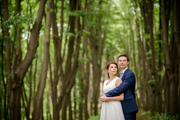 Fototapeta premium Bride and Groom at wedding Day walking Outdoors on spring nature. Bridal couple, Happy Newlywed woman and man embracing in green park. Loving wedding couple outdoor.