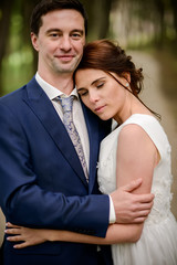 Bride and Groom at wedding Day walking Outdoors on spring nature. Bridal couple, Happy Newlywed woman and man embracing in green park. Loving wedding couple outdoor.