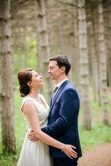 Bride and Groom at wedding Day walking Outdoors on spring nature. Bridal couple, Happy Newlywed woman and man embracing in green park. Loving wedding couple outdoor.