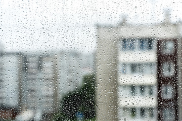 rain drop on window glass with blur houses in background