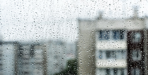 rain drop on window glass with blur houses in background