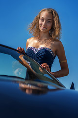 Junge Frau lehnt an der Windschutzscheibe eines Cabriolets 3