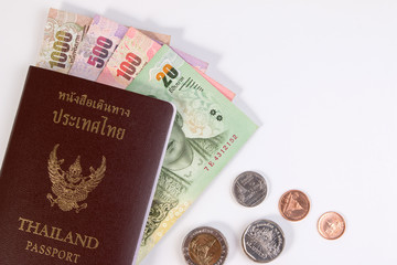Thai Passport with Thai money banknote and Thai coin isolated on white. The passport of Thai citizen on Thai banknote.