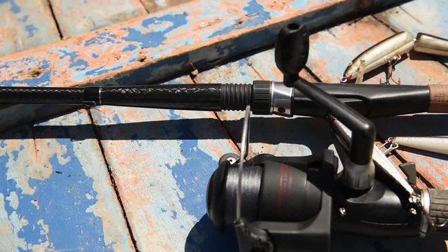 A carbon fishing rod with lures over an old wood plank - pan