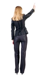 Back view of young blonde business woman pointing at wall . beautiful girl in dark suit. Rear view people collection. backside view of person.  Isolated over white background.